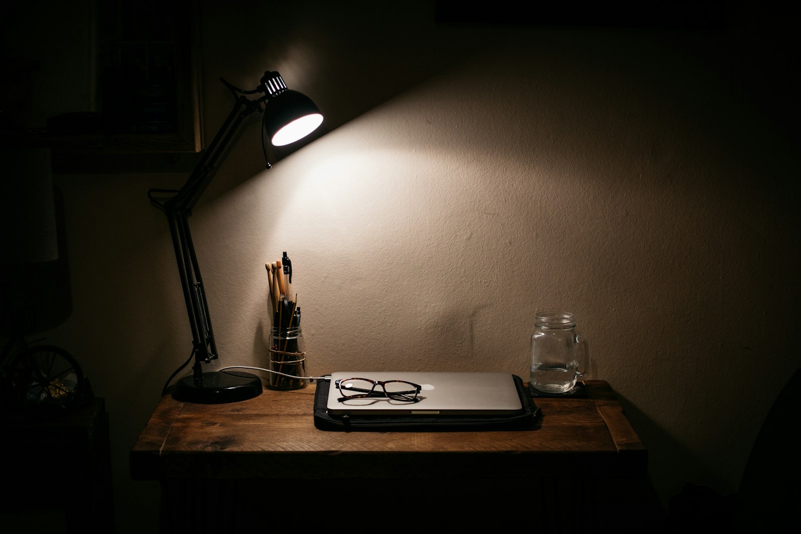 A single desk lamp lighting a wooden desk late at night