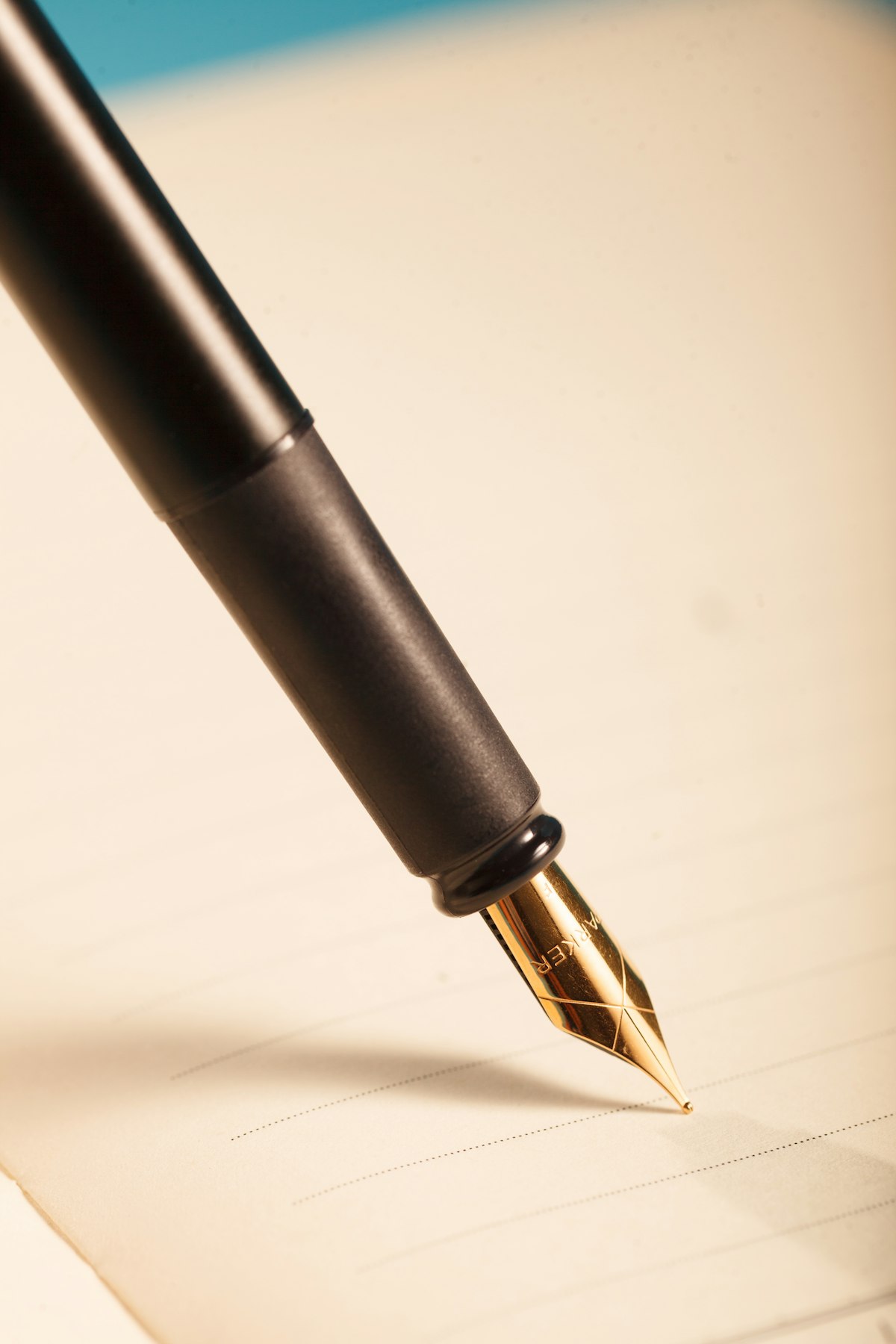 A black fountain pen resting on cream paper, nib down