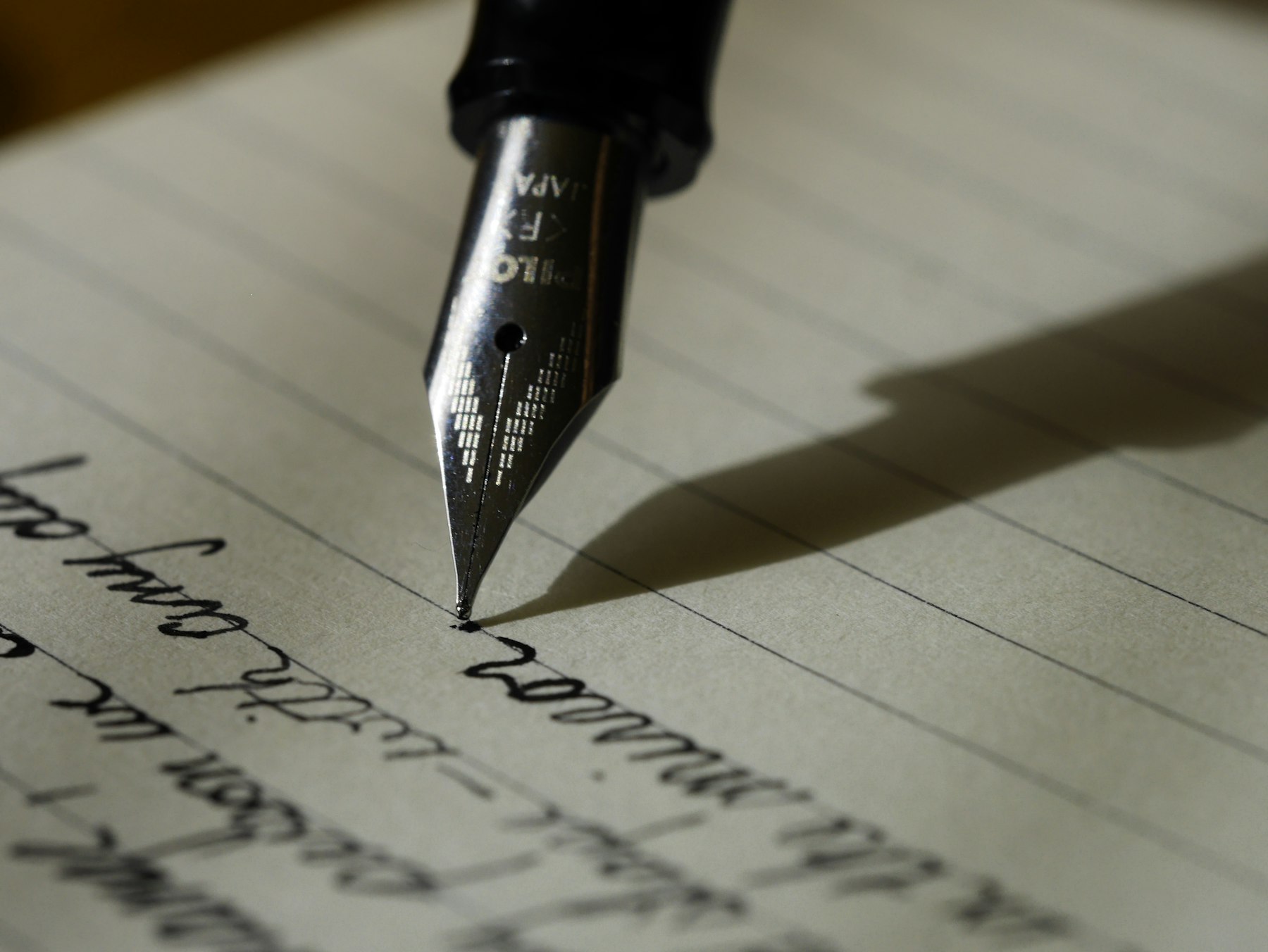 A fountain pen writing a handwritten letter on lined paper