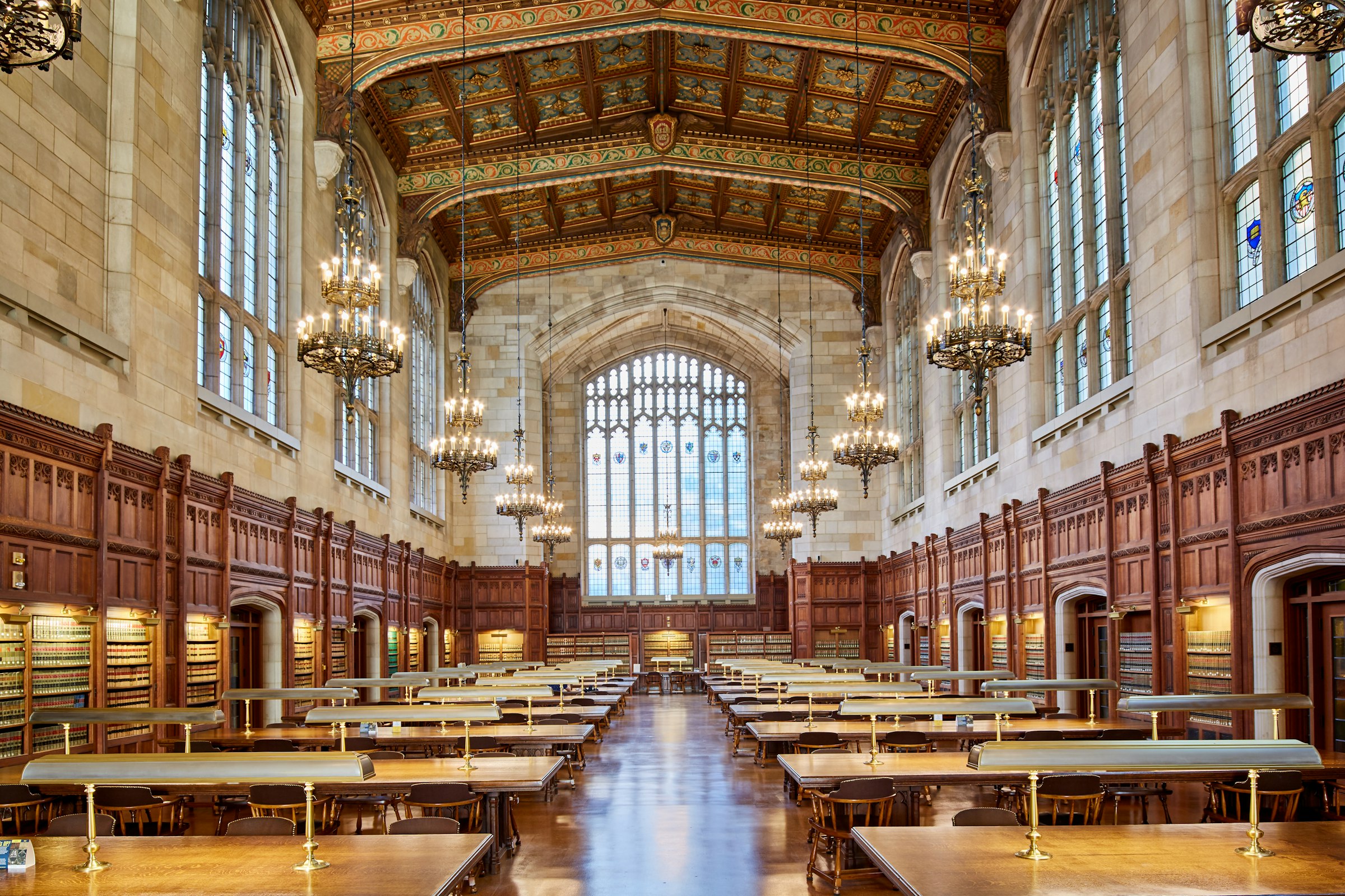 A long, wood-panelled law library reading room with chandeliers and rows of desks